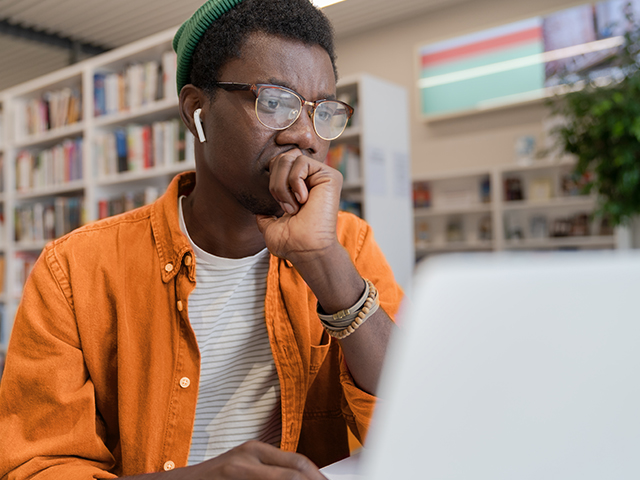 Closeup of african american male student using laptop in a library