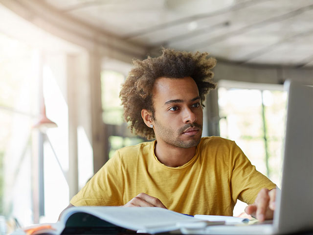 male student studying with laptop