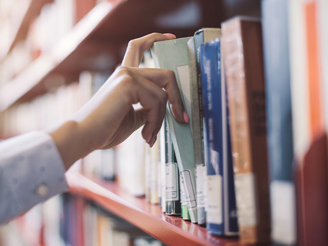 Student taking out book from bookshelf