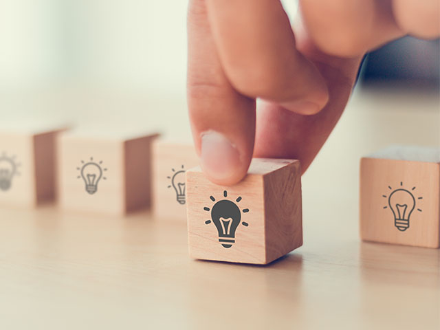 Person holding wooden block with lightbulb icon