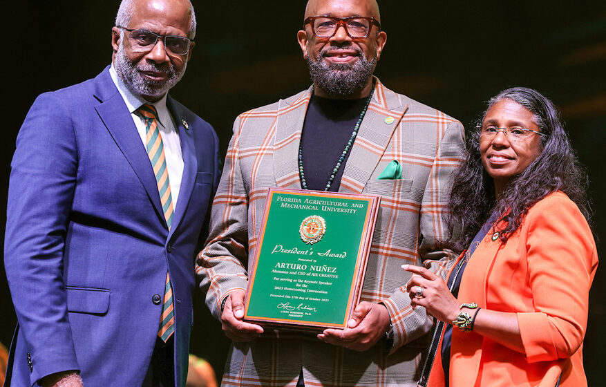 President Larry Robinson recognized speaker Arturo Nuñez (center) standing with his former classmate Shawnta Friday-Stroud, SBI dean and vice president for University Advancement. (Credit: Glenn Beil)