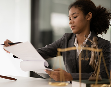 A professional woman lawyer in business attire holding and reviewing a document in her hand