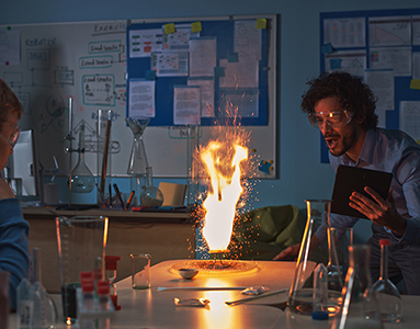 A man holding a tablet in a classroom setting, conducting a physics experiment