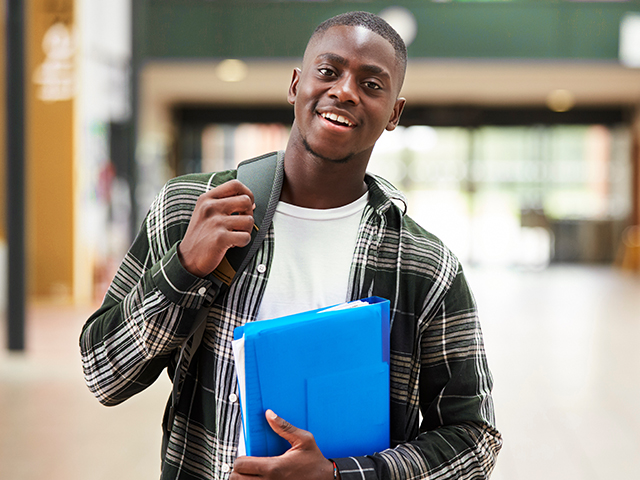 smiling African American male college student with backpack, holding folders