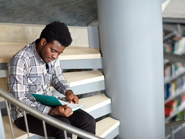 young female student reading a book at a table in the library