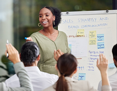 A woman PR professional presenting to a group, engaging them with a sales strategy and brand communication presentation.