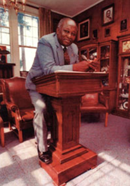 Dr. James N. Eaton (1930-2004), founder and first director of the Black Archives, pictured in historic Carnegie Library posed behind an antique lectern used by famous guests visiting the campus of Florida A&M University. These special visitors included leaders such as Booker T. Washington, Mary McLeod Bethune, James Weldon Johnson, and Thurgood Marshall. 
