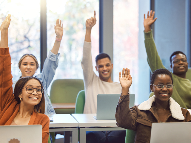 classroom with students with their hands raised and excited