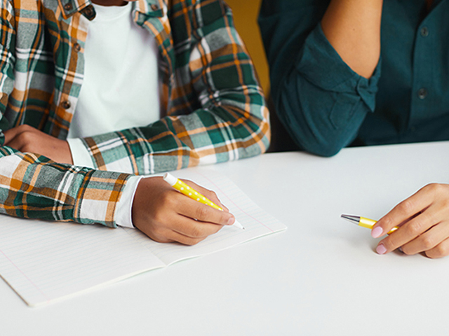 Close up of hands doing school work. Student and Tutor Close up of hands doing school work. Student and Tutor