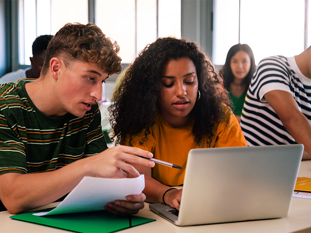 man and woman looking at laptop in class