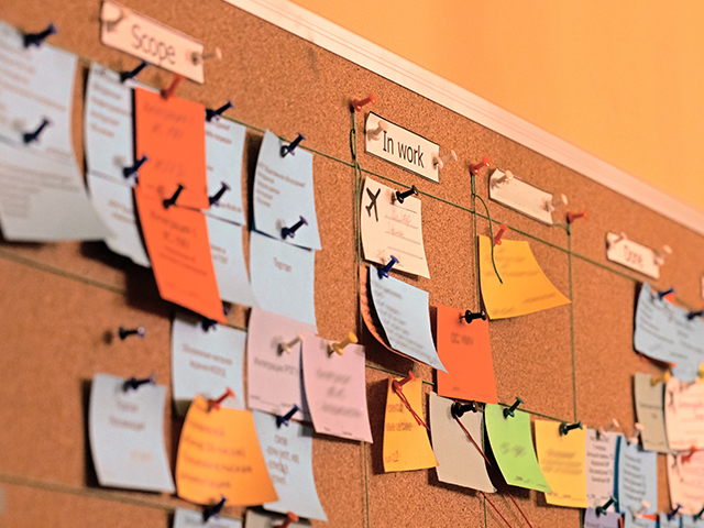 Close up office bulletin board/ task board with sticky notes and pins