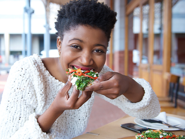 Close up portrait of an happy african american woman eating a veggie pizza