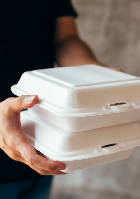 Close-up of hands holding a stack of two styrofoam food container boxes