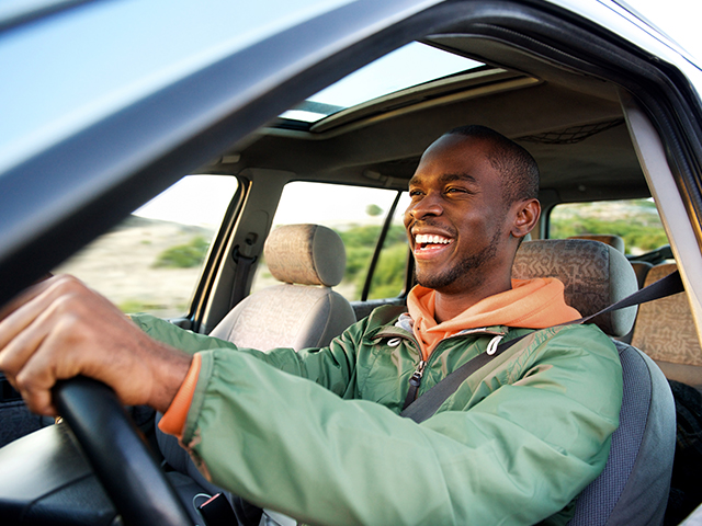 Side portrait of happy african american man driving car