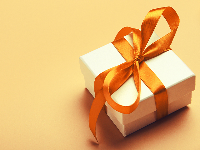 White gift box with orange bright ribbon on yellow background