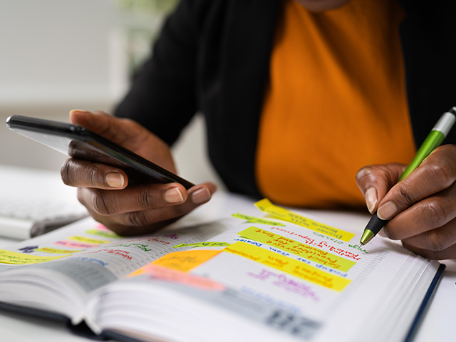 person writing in a planner notebook