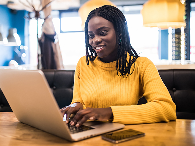 Girl in yellow sweater using laptop