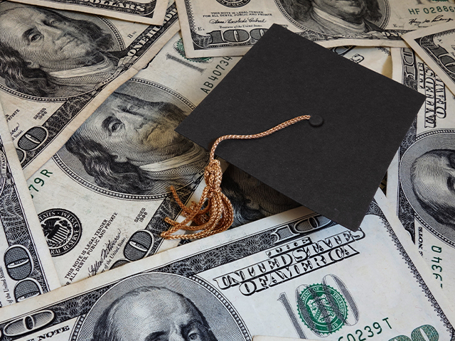 Black Graduation cap sitting on a pile of money