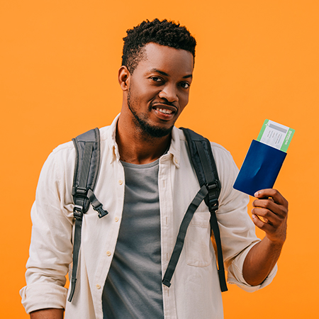 smiling black man with backpack holding passport infront of orange background