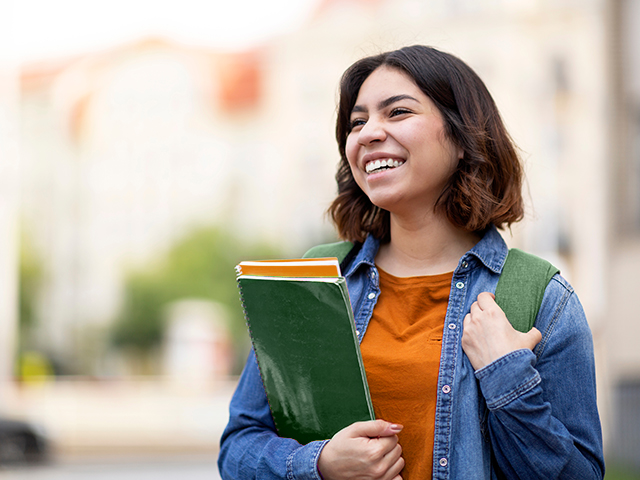 female student holding books smiling