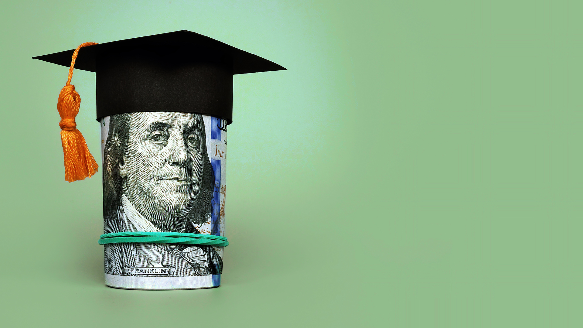 Roll of money with paper graduation cap on top