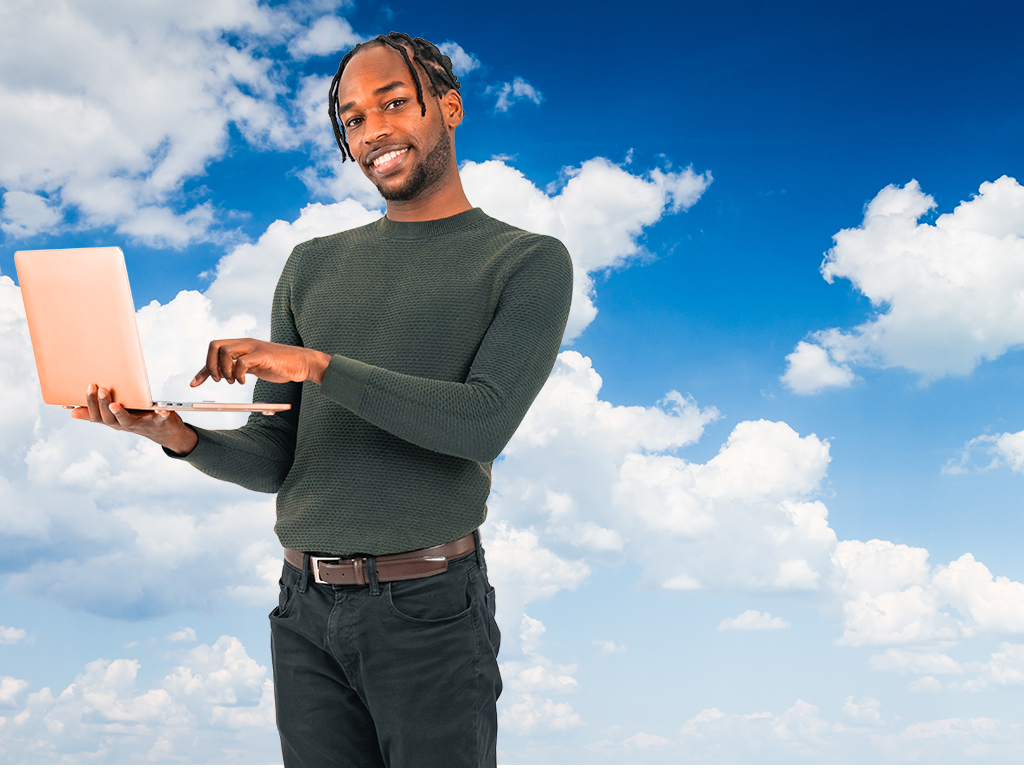 Person holding an open laptop, with a blue skay and white clouds as the background.