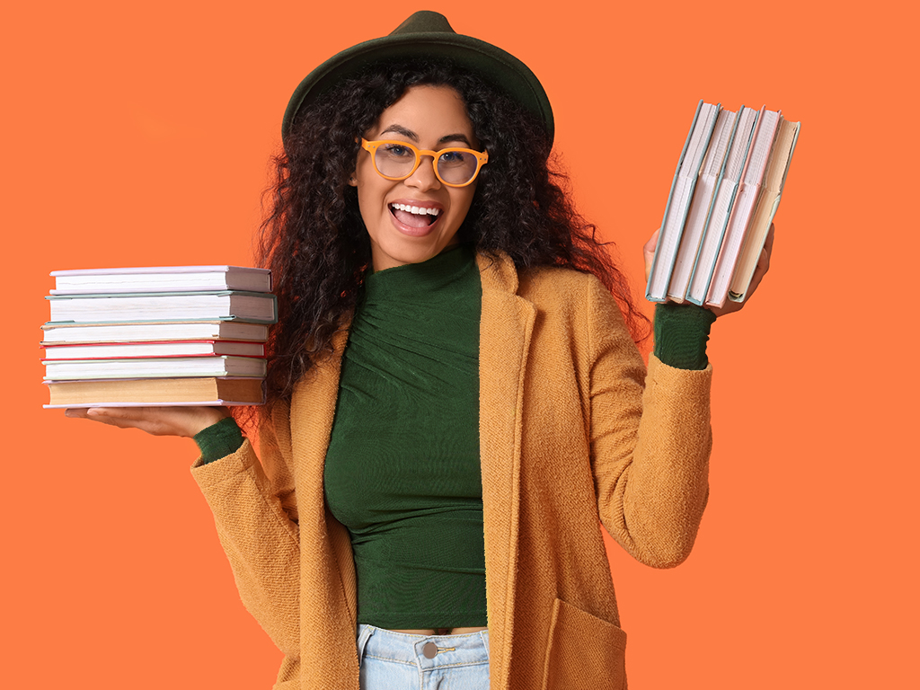 A young woman holding a stack of books in each hand.