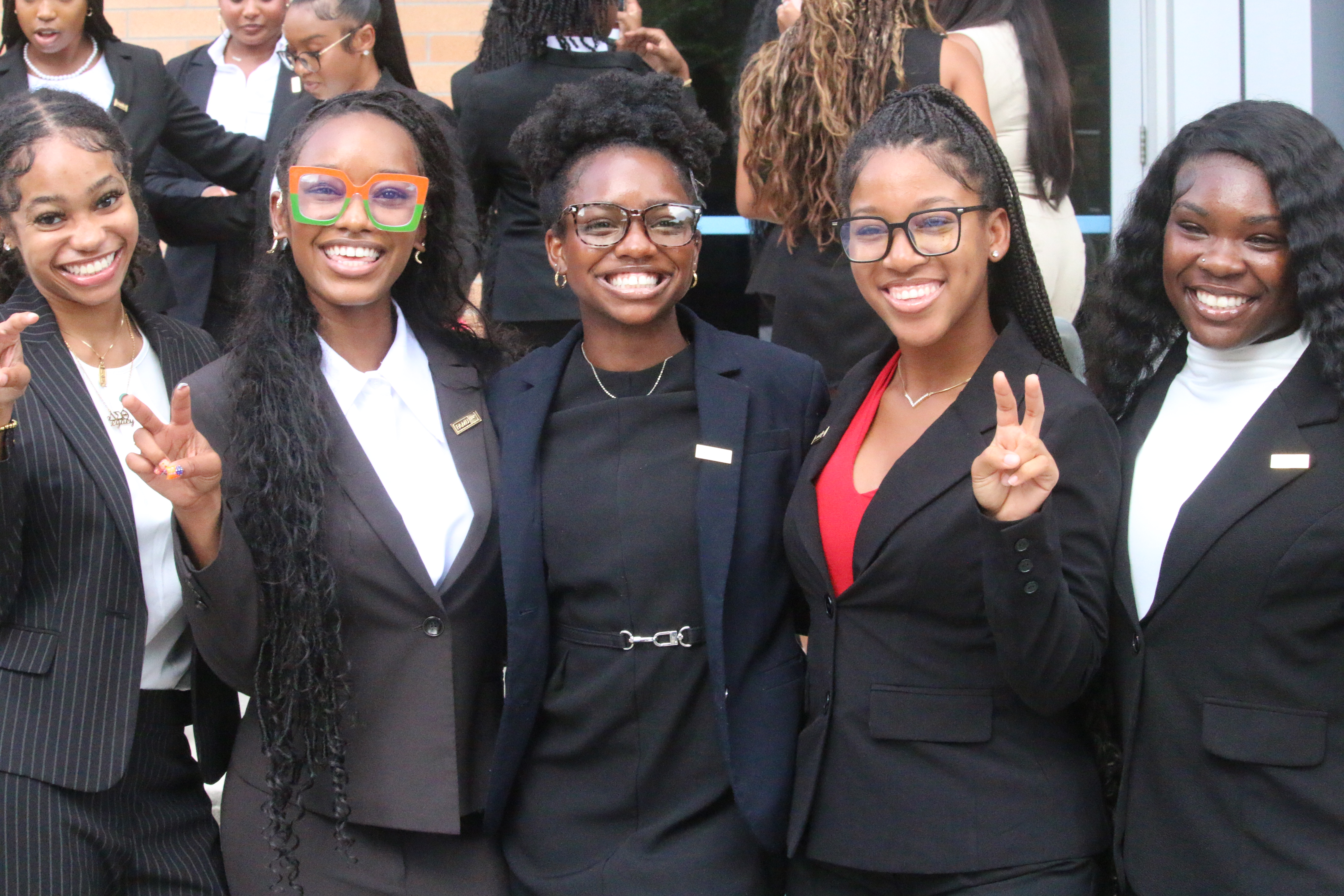 Five female students smiling with three of them holding up the strike pose