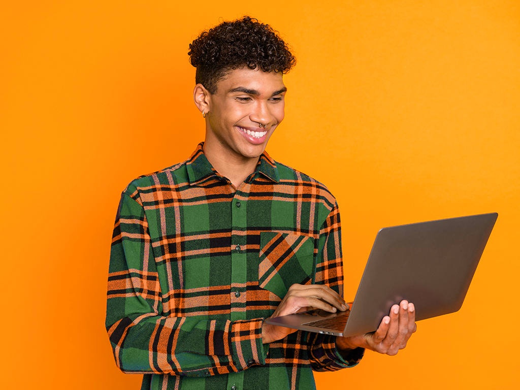 Male student Male student holding and using a silver laptop