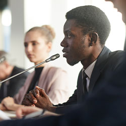 male student sitting speaking on a table mic