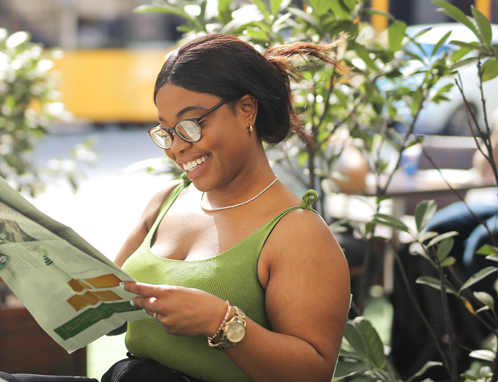 a girl outside reading a newspaper