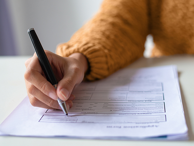 Close up of hand filling out a paper document form