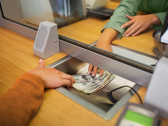 At Caheirs' office, a clerk accepts cash from a customer.