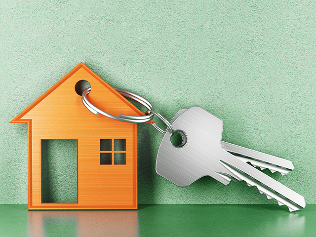A keyring with a small orange house-shaped keychain and two silver keys, set against a green textured background
