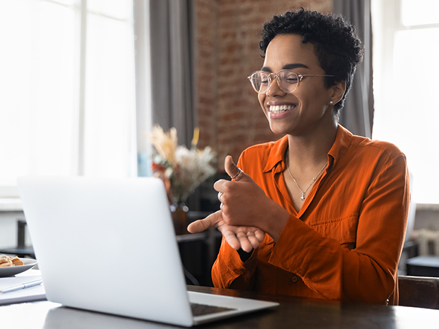 Smiling African American woman in glasses talking on video call using sign language