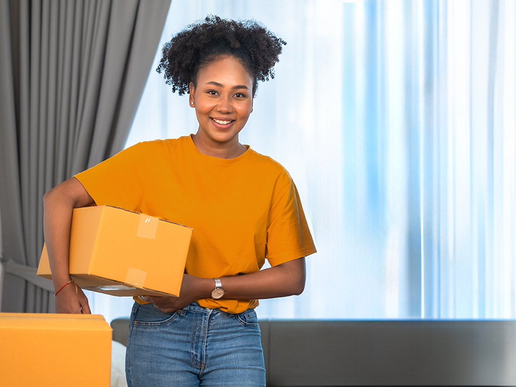 A smiling girl holding moving boxes 