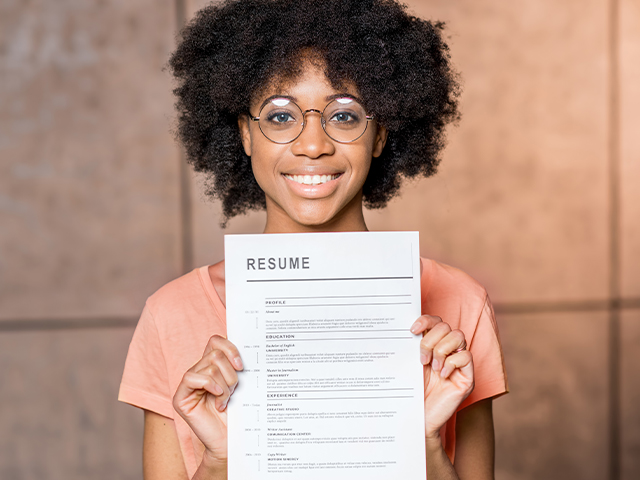 a young african woman smiling and holding resume document